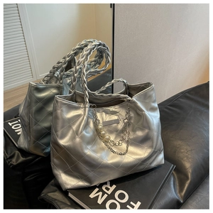 Detail of silver quilted tote bag with chunky woven handle and pearl chain charm