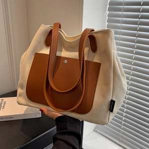 Minimalist off-white canvas tote bag with brown leather handles and large front pocket