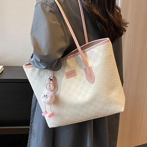 Chic cream woven tote bag with pink leather trim and fluffy charm shown on model