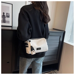 Detail of white mini pillow bag with black strap and Fashion label on a model