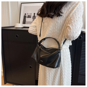 Detail view of the black leather satchel bag with wide handle on a white lace dress