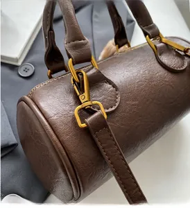 Close-up of premium dark brown Boston bag with vintage golden hardware and lychee texture