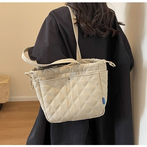 Detail of beige quilted canvas tote bag with drawstring closure and front pocket