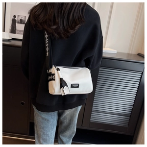 Gros plan d'un sac bandoulière blanc avec sangle large et logo sur fond moderne