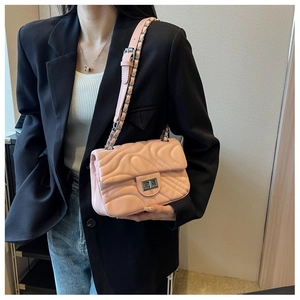 Detail of pink quilted chain bag with silver twist lock on a black blazer outfit