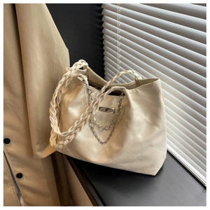 Detail of cream woven tote bag featuring diamond quilting and pearl chain accents