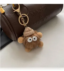 Close-up of cute monster plush keychain in brown fur on a stylish leather boston bag