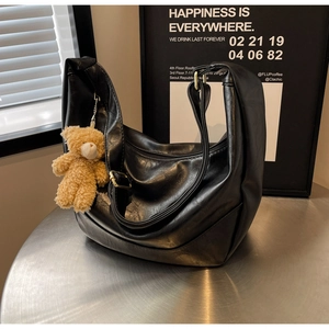 Detail of black pleated hobo bag with adjustable strap and cute brown bear pendant