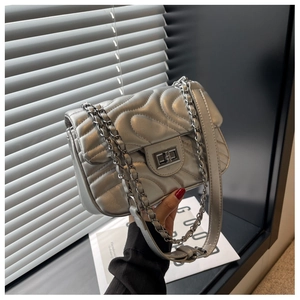 Macro detail of silver quilted bag showing wavy stitching and metallic twist lock