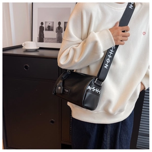 Détail du sac bandoulière cylindrique noir avec large sangle FASHION et texture en cuir