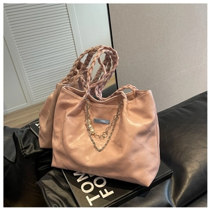 Detail of pink quilted tote bag with woven handles, pearl charms and metal hardware