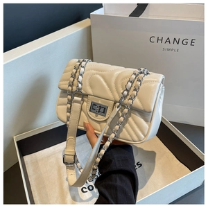 Detailed view of quilted cream chain bag with silver twist lock and gift packaging