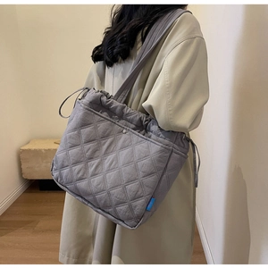 Quilted gray tote bag with drawstring closure shown on shoulder for daily styling