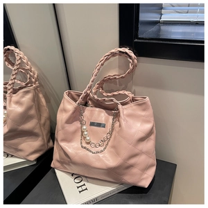 Detail of pink quilted tote bag with pearl chain and woven handle on modern display