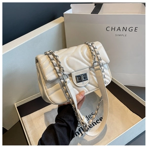 Detailed close-up of cream quilted crossbody bag with silver rotating lock and chain