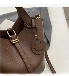 Detail view of coffee brown bucket bag with lychee texture leather and gold hardware