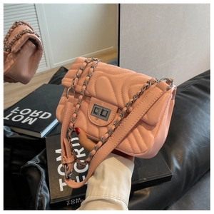 Detail of pink quilted crossbody bag with silver twist lock and metal chain strap