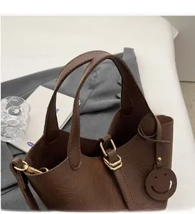 Detail of dark brown pebble leather tote bag featuring gold hardware and a charm