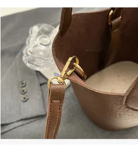 Detailed close-up of premium gold hardware on a dark brown leather bucket handbag