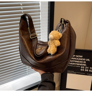 Detail of dark brown retro crescent tote bag with a cute plush bear charm hanging on zipper