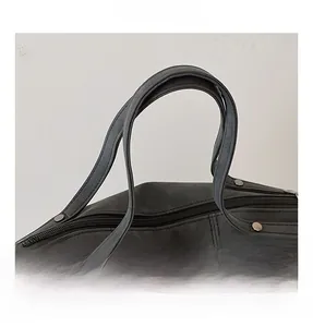Dettaglio del manico della borsa in pelle scamosciata grigio scuro con borchie e zip