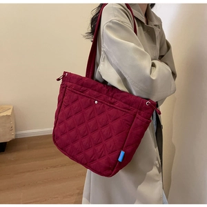 Close-up of quilted burgundy tote bag showing rhombus pattern and soft padded texture