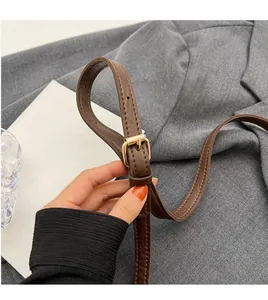 Detail of adjustable brown leather strap with gold buckle and fine stitching