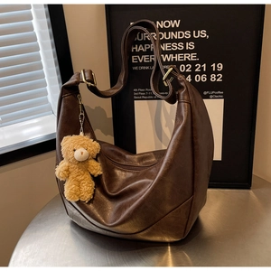 Detail of vintage dark brown crescent bag with adjustable strap and plush bear charm