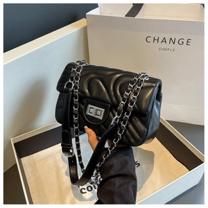 Detail of black quilted chain crossbody bag featuring a silver twist lock and gift packaging