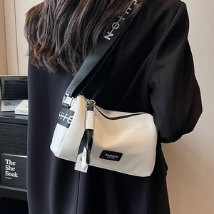 White pebbled leather crossbody bag with black logo wide strap on a model