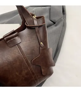 Gros plan détaillé d'un sac seau marron rétro en cuir avec pendentif étoile et coutures