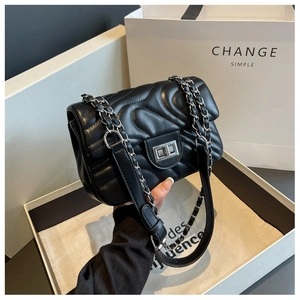Detail of black quilted leather shoulder bag with silver chain strap and metal clasp