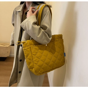 Detailed view of mustard yellow quilted tote bag with drawstring and rhombus pattern