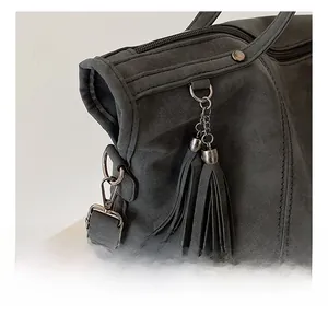 Dettaglio del gancio in metallo e delle frange in scamosciato sulla borsa tote grigio retrò