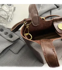 Détail du sac seau en cuir marron foncé avec ferrures dorées et fermeture magnétique