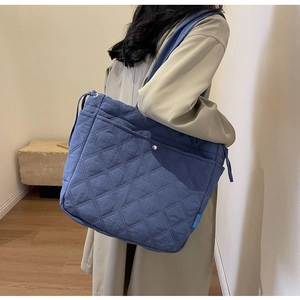 Close-up of blue quilted tote bag showing diamond stitch pattern and durable shoulder strap