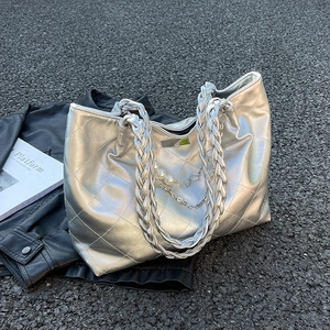 Silver quilted tote bag with chunky woven strap and pearl floral charm on urban background