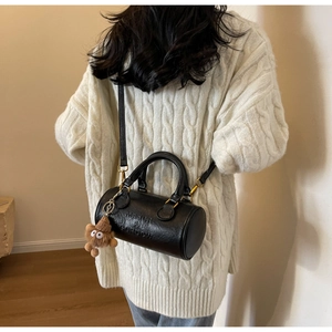 Detail of black leather Boston bag with embossed logo and cute brown plush bear charm