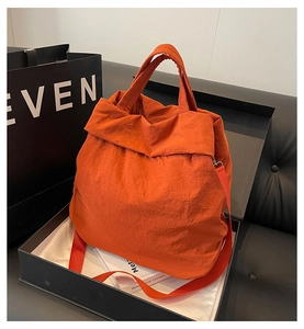 Detailansicht der orangefarbenen Nylon-Tragetasche mit Doppelgriffen in einer Geschenkbox