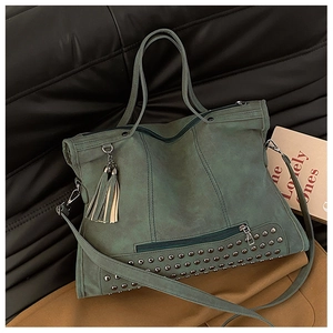 Dettaglio della grande borsa tote in pelle scamosciata verde scuro con borchie e nappe