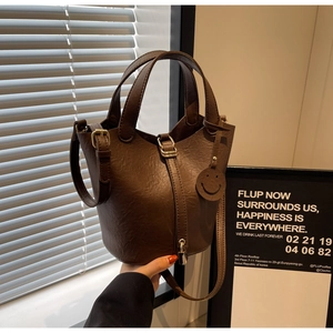 Detail of dark brown bucket bag with lychee texture leather and gold metal lock buckle