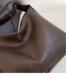 Detail of soft dark brown leather texture with oil-wax finish on the crossbody shoulder bag