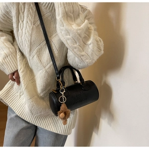 Detail of black Boston bag with embossed lettering and a cute brown fuzzy bear charm