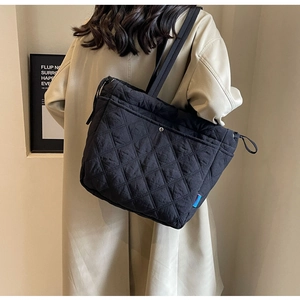 Detail of black quilted tote bag with diamond stitching and adjustable side drawstrings