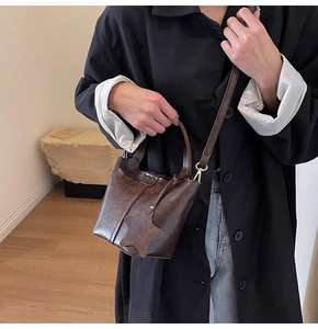 Détail du sac seau vintage en similicuir marron foncé avec breloque étoile et bandoulière