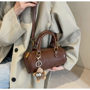 Detailed macro view of brown cylinder Boston bag with MAJCR & GORDOW embossed text