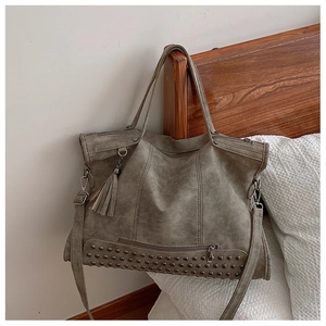 Dettaglio borsa tote retrò grigia con rivetti decorativi e ciondolo nappa elegante