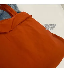Detailaufnahme der weichen orangen Nylon-Stoffstruktur einer großen Bucket-Tasche