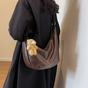Retro dark brown crescent shoulder bag with plush bear charm on model in black coat