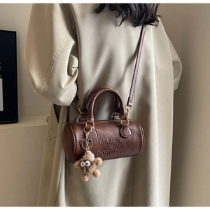 Deep brown Boston cylinder bag detail with embossed text and plush pendant